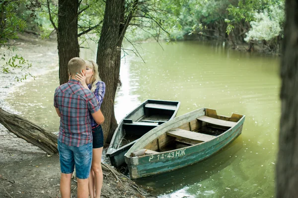 Ερωτευμένος ο τύπος και το κορίτσι περάσουν χρόνο περπατώντας στην όχθη του ποταμού σε βάρκες φόντο — Φωτογραφία Αρχείου