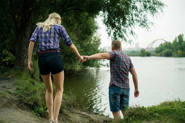 Aşık adam ve kız zaman harcamak tekneler arka plan nehir kıyısında yürürken — Stok fotoğraf