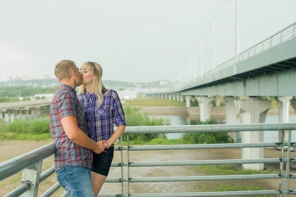 Άνδρας και γυναίκα στο καρό πουκάμισο φιλί χαριτωμένο Αγκαλιάζοντας στέκεται στις σκάλες της γέφυρας — Φωτογραφία Αρχείου