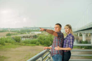 romantik yürüyüş adam kız parmak mesafe içine gösterir. seven çift kadar ilerisini arıyorum. gelecek için planlar yapmak. Kız ekose gömlek ve şort. Erkek pantolon ve ekose gömlek. Bulutlu yaz gün.