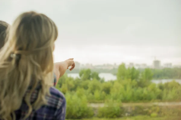 romantic stroll guy shows girl finger into the distance. loving couple looking far ahead. make plans for future. girl in plaid shirt and shorts. Man in pants and plaid shirt. cloudy summer day.