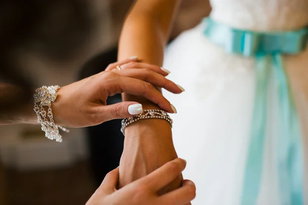 Flicka rätar hans händer armband smycken på brudens handled — Stockfoto