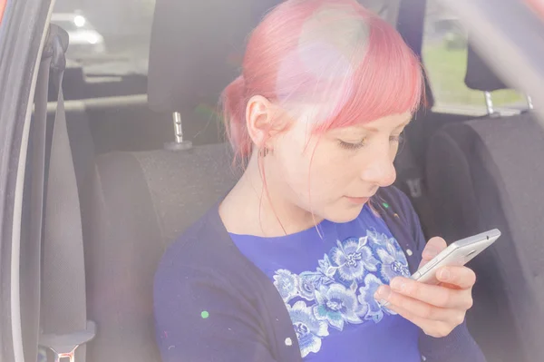 Chica con el pelo rosa ver imágenes en la pantalla de su teléfono inteligente —  Fotos de Stock