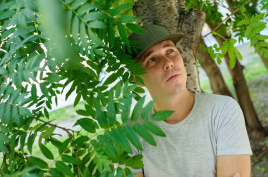 genç adam standart fiziksel yeşil çalılar bir arka sokakta poz