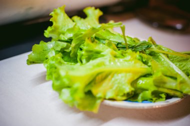 yeşil salata yaprakları bir plaka üzerinde yatıyordu. ve hazır yemek pişirmek için su ile yıkanmış
