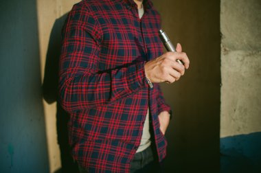 adam bir ekose gömlek ve pantolon ishal vape suyu elektronik sigara. O mekanik bir mod ile BKİ tutar. 