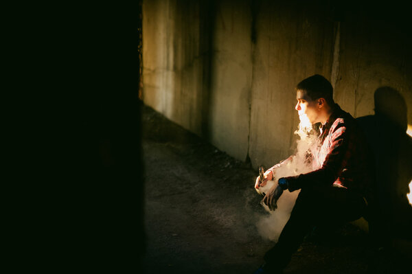 man in a plaid shirt and jeans, smokes an electronic cigarette