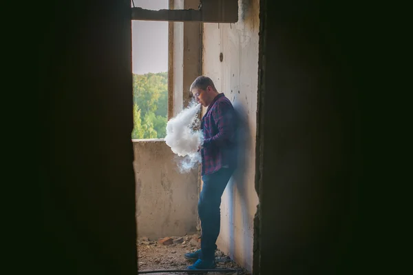 Чоловік у плетеній сорочці та джинсах, курить електронну сигарету — стокове фото