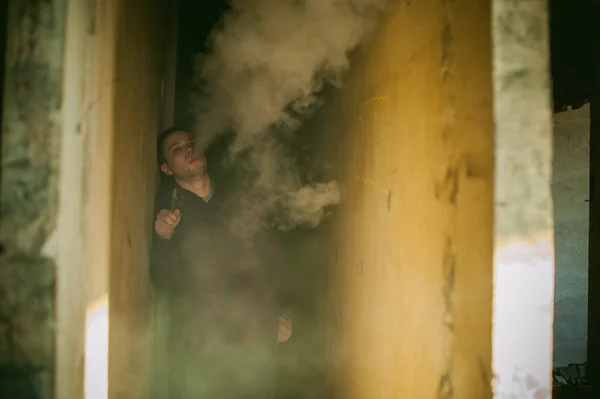 Adam bir ekose gömlek ve kot pantolon, elektronik sigara içiyor — Stok fotoğraf