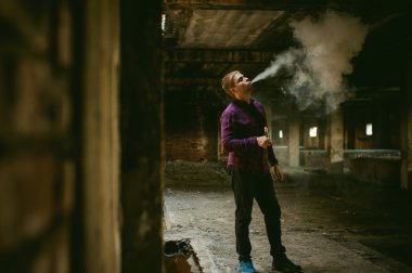 adam bir ekose gömlek ve kot pantolon, elektronik sigara içiyor