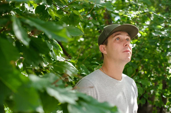 guy standard physique posing on the street on a background of green bushes