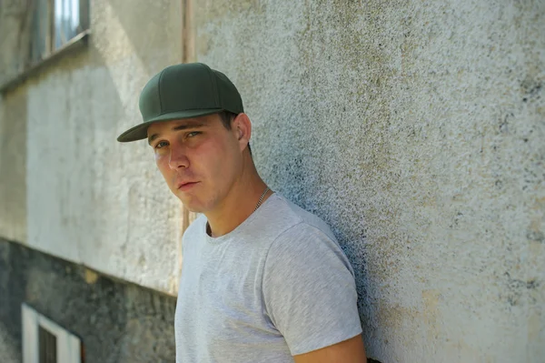 guy standard physique posing on the street on a background of green bushes