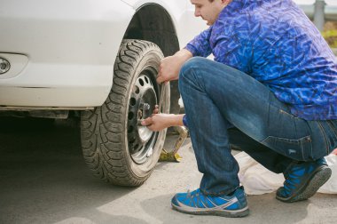 adam bir tekerlek yolda değiştirme. yolda tekerleğin kırılması, delik, araba jack kaldırın ve tekerlek fındık gevşeterek tarafından kaldırmak gerekli. yol sorunları yolcuları. Kendin yap