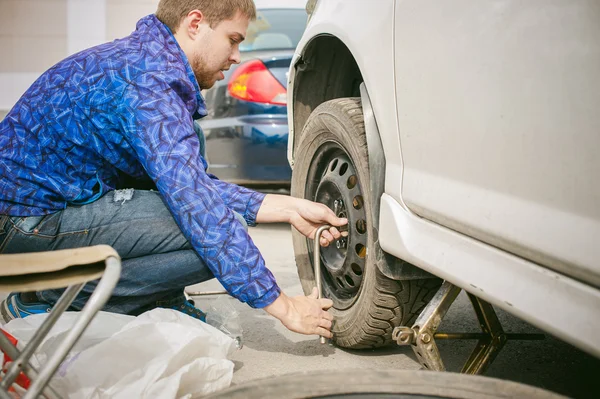 man changing a wheel on the road. on way there was breakage of wheel, puncture, necessary to lift the car jack and remove the wheel by loosening the nuts. road problems travelers. do it yourself