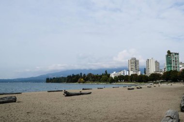 English Bay, Vancouver, Kanada - 4 Ekim 2025: Bulutlu bir günde açık plaj ve arkada fotokopi alanı olan bir bina.