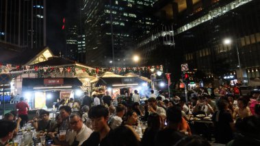Lau Pa Sat, Raffles Quay, Singapur - 14 Ağustos 2025: Viktorya döneminden kalma yeniden inşa edilmiş Hawker Center 'ın önünde şiş yiyen ve şarap içen insanlarla dolu açık hava pazarı. 