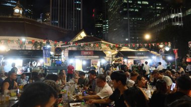 Lau Pa Sat, Raffles Quay, Singapur - 14 Ağustos 2025: Viktorya döneminden kalma yeniden inşa edilmiş Hawker Center 'ın önünde şiş yiyen ve şarap içen insanlarla dolu açık hava pazarı. 