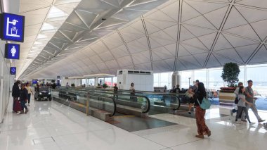 Hong Kong Uluslararası Havaalanı, Hong Kong - 1 Ekim 2025: Gündüz vakti havaalanının hava yolunda yürüyen turistler