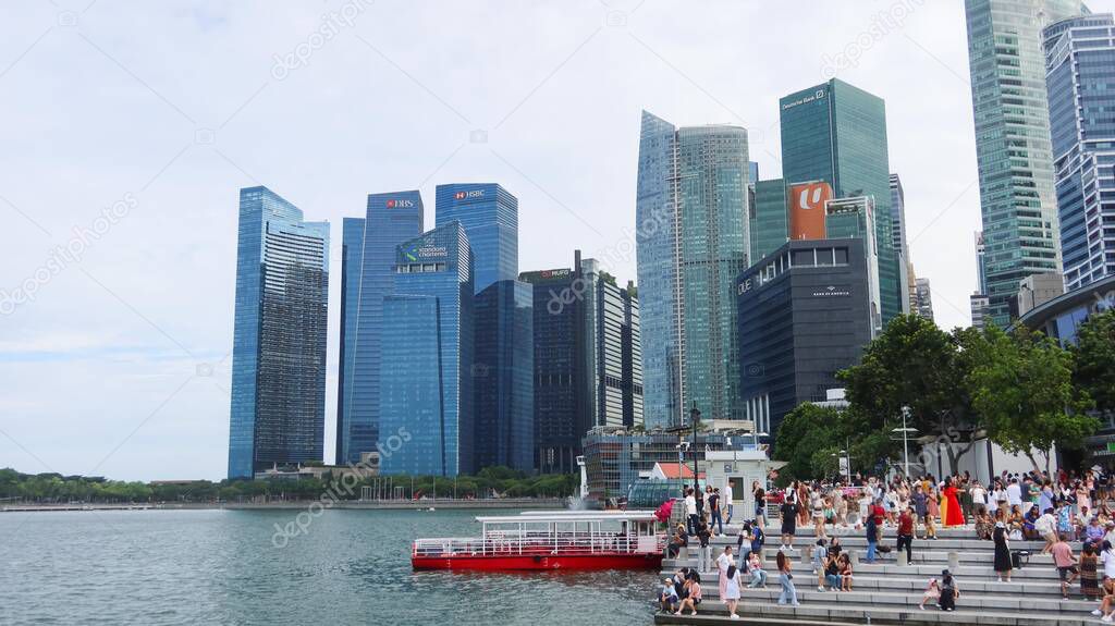 Merlion Park, Marina Bay, Singapore- 13 Aug 2025: waterfront with Merlion and lots of tourists sitting and standing on the steps, enjoying the view, with it shows skyline of Singapore Centre District