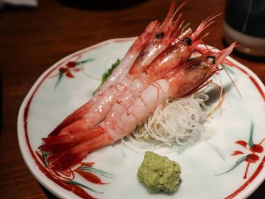Japon çiğ çiğ sashimi yakın çekim kabuğu kaldırılmış üç karides sashimi, bir çiçek tabağı ve yanında wasabi