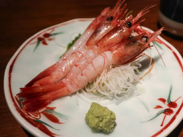 Japon çiğ çiğ sashimi yakın çekim kabuğu kaldırılmış üç karides sashimi, bir çiçek tabağı ve yanında wasabi