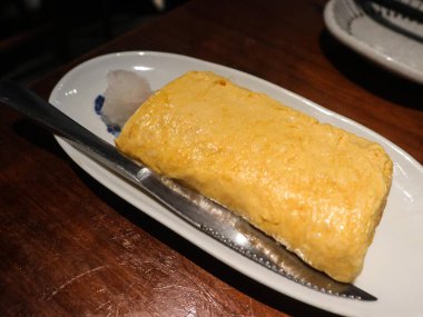 Japon Tamagoyaki (yumurta omleti rulosu) 'nin tamamını kapatın. Yanında da kopyalanmış turpla birlikte.