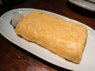 Japon Tamagoyaki (yumurta omleti rulosu) 'nin tamamını kapatın. Yanında da kopyalanmış turpla birlikte.