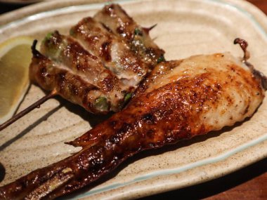 Izakaya restoranında ızgarada ızgara tavuk kanadı ve domuz etiyle sarılmış kuşkonmaz. 