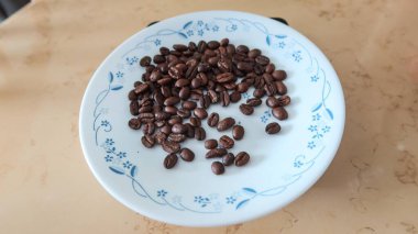 Fotokopi alanı olan beyaz ve mavi bir tabağa dağılmış kahve çekirdeklerini kapatın.