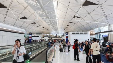 Hong Kong Uluslararası Havalimanı, Chek Lap Kok, Hong Kong - 1 Ekim 2025: Geometrik bal peteği tavanlı turistler havaalanı terminali boyunca yürüyorlar