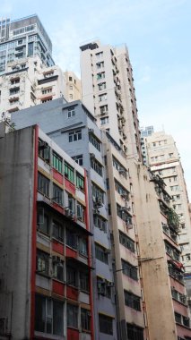 Queen 's Road, Wan Chai, Hong Kong - 15 Kasım 2025: Gündüz vakti dış duvarında klima olan renkli, yırtık eski apartman dairelerinin dikey fotoğrafı
