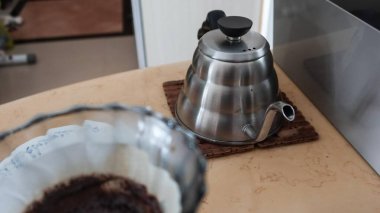 Bir filtre kağıdıyla çaydanlık demleyen gümüş bir eli kapat ve kopyalama alanı ile filtreden aşağı boşalt