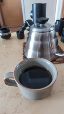 Sıcak, sade bir kahve bardağını kapat ve arkada çay demleyen gümüş bir el fotokopi alanı ile kahveyi hazırlamak için.