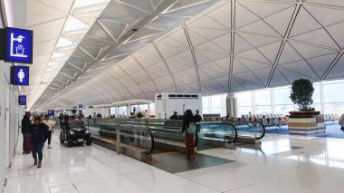 Chep Lap Kok, Hong Kong Uluslararası Havaalanı, Hong Kong - Ekim 12025: Koridorda yürüyen, yürüyen ve elektrikli taşıt arabası olan insanlar