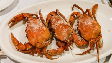 close up of three orange Cantonese cooking style Salt-Crusted Baked Virgin Crabs with copy space