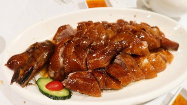 Çin usulü ızgara kavurma, çıtır derili ve fotokopi alanlı klasik siu mei (kızarmış et) ve yanında da salatalık dilimi.