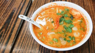 Tayland usulü baharatlı ve ekşi Tom Yum Gong çorbası karides, kalamar, baharat ve kişniş karışımı sokak satıcıları dükkanında kaşıkla servis edilir.
