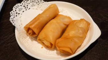 Karides ve domuz etiyle doldurulmuş üç Çin Dim Sum böreğini fotokopi uzayı ile birlikte beyaz bir tabağa koy.