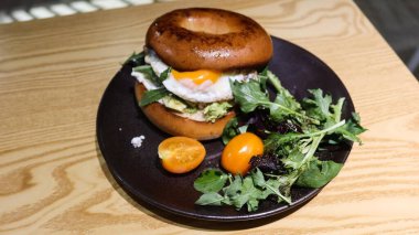 Yumurta, avokado ezmesi ve roket sebzesi, salata ve vişneli domates ile doldurulmuş domuz pastırması siyah bir tabakta fotokopi alanı ile birlikte.