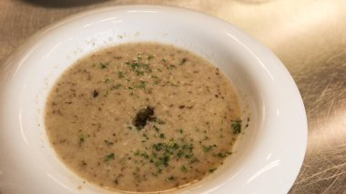 Beyaz kase kremalı mantar çorbasına yakın doğranmış otlarla süslenmiş, metalik bir yüzeyde fotokopi alanı ile servis edilmiş.