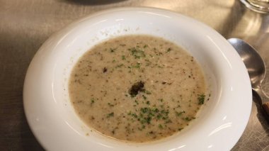 Beyaz kase kremalı mantar çorbasına yakın doğranmış otlarla süslenmiş, metalik bir yüzeyde fotokopi alanı ile servis edilmiş.