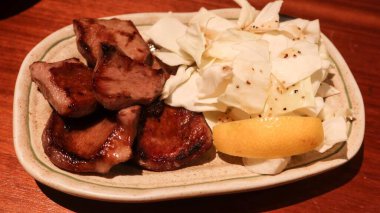 Japon ızgara öküz dilini kapatın. Yanında lahana ve limon dilimi ile dilimleyin. Kopya alanı olan bir izakaya restoranında.