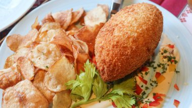 Geleneksel Ukrayna tavuğu Kiev 'in (tavuk yahnisi) yanına yağlı yumurta ve yanında patates cipsi ile birlikte ekmek kırıntılarıyla kaplanmış yağda kızartılmış tavuk filetosu.