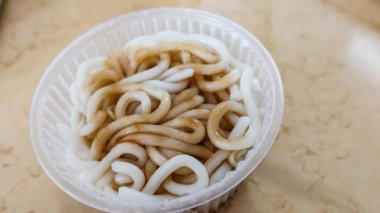 Şeffaf plastik bir kasede soya soslu haşlanmış Japon udon şehriyesini fotokopi alanı olan bir masaya koy.