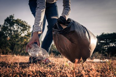 İnsan eli plastik şişeyi ve çöpü doğada tutar.
