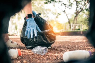 Plastik çöp taşıyan gönüllü atıkları düzgün bir şekilde atmak için temizler.
