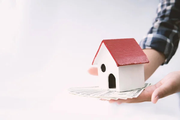 Human hand protects wood house model, the residential crisis in the covid-19 situation.