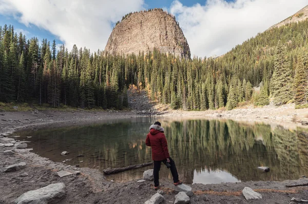 Man photographer standing on Mirror Lake in autumn forest near Lake Louise at Banff national park, Canada