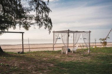 Ahşap bir barınak ve plaja kurulmuş şezlonglar.
