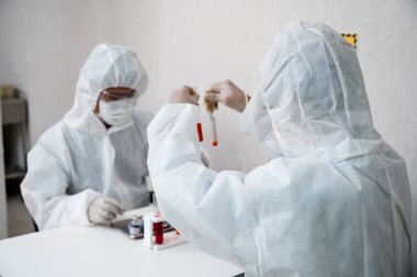 PPE 'deki araştırmacılar ve asistanlar laboratuardaki test tüpündeki kan örneğini analiz ediyorlar.